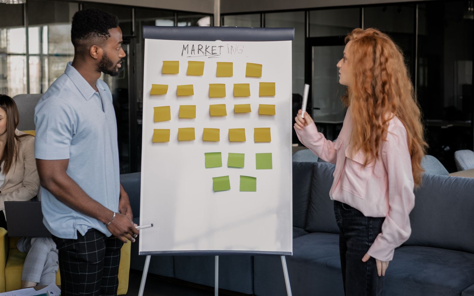 Two colleagues planning a media revenue strategy on a whiteboard